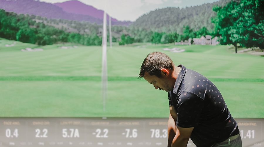 Man teeing up on Trackman indoor driving range